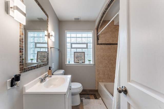 full bathroom featuring vanity, toilet, a wealth of natural light, and tiled shower / bath combo