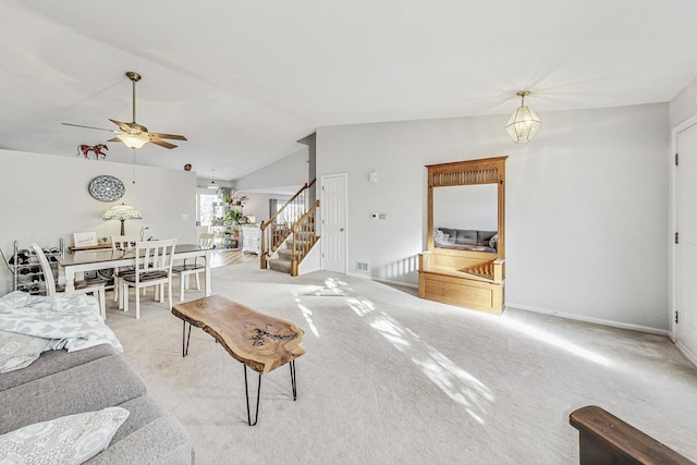 carpeted living room featuring ceiling fan with notable chandelier and vaulted ceiling