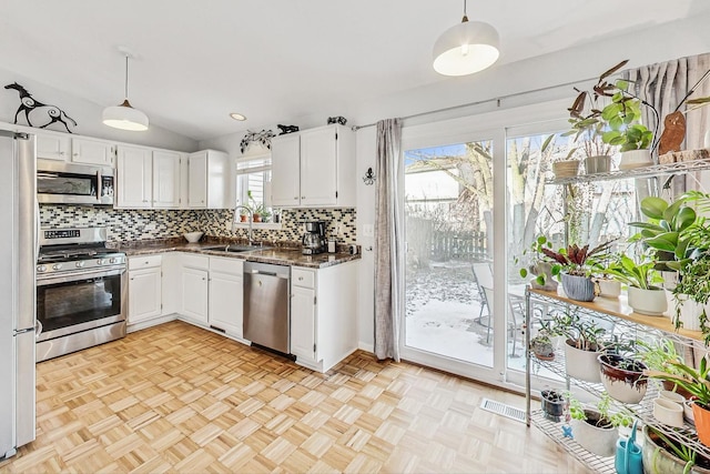 kitchen featuring sink, white cabinets, decorative light fixtures, and stainless steel appliances