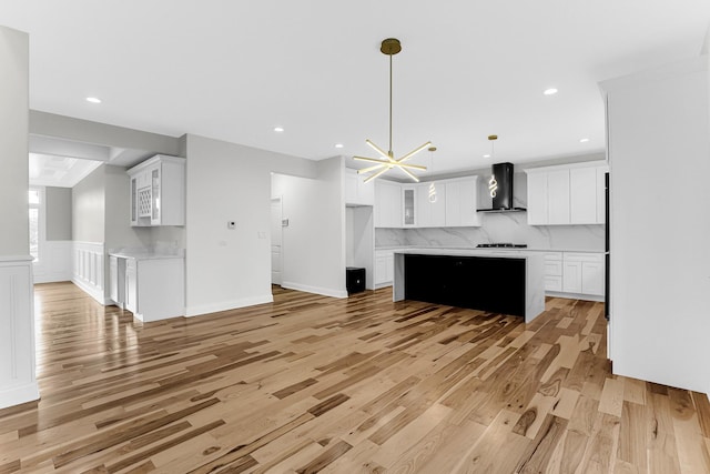 kitchen with white cabinets, pendant lighting, a center island, and wall chimney range hood