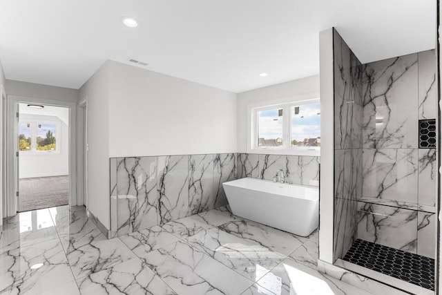 bathroom featuring separate shower and tub and tile walls