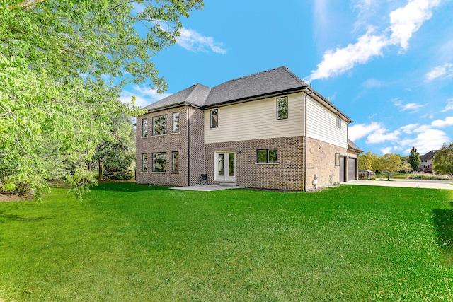 rear view of house featuring french doors, a yard, and a garage