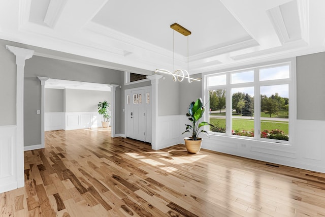 unfurnished dining area featuring ornamental molding, decorative columns, a raised ceiling, and light hardwood / wood-style floors