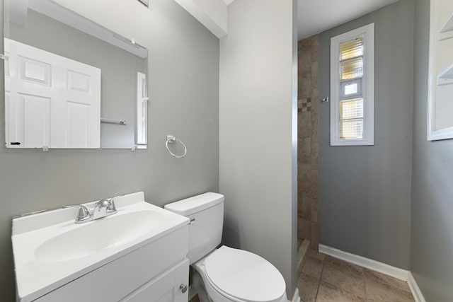 bathroom with toilet, vanity, tiled shower, and tile patterned floors