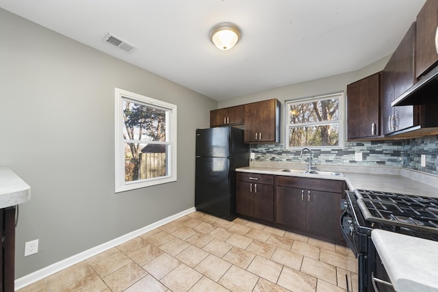 kitchen featuring black appliances, wall chimney exhaust hood, a healthy amount of sunlight, and sink