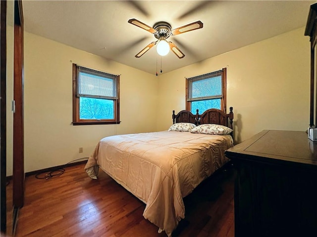 bedroom with ceiling fan, dark hardwood / wood-style floors, and multiple windows