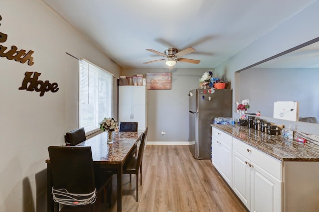 kitchen featuring white cabinets, stainless steel fridge, dark stone countertops, and light hardwood / wood-style flooring