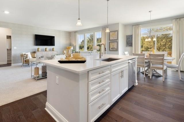 kitchen with dishwasher, hanging light fixtures, a center island with sink, white cabinetry, and sink