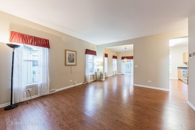 spare room featuring a wealth of natural light, a notable chandelier, and hardwood / wood-style flooring