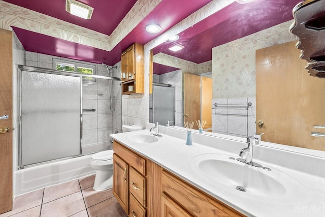 full bathroom with tile patterned floors, vanity, tile walls, enclosed tub / shower combo, and toilet