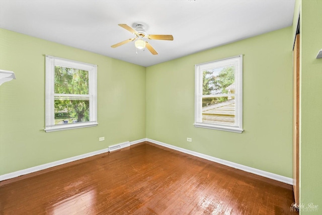 empty room with a wealth of natural light, hardwood / wood-style floors, and ceiling fan