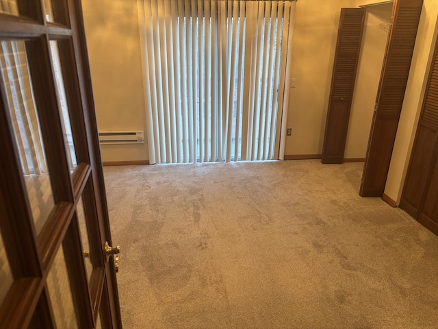 spare room featuring light colored carpet and a baseboard heating unit