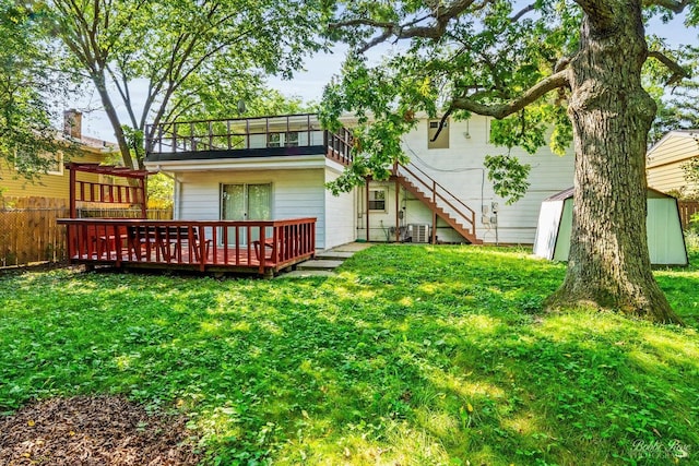 back of house with a wooden deck, a yard, central AC, and a storage shed