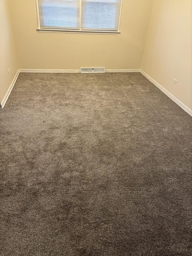 spare room featuring dark carpet