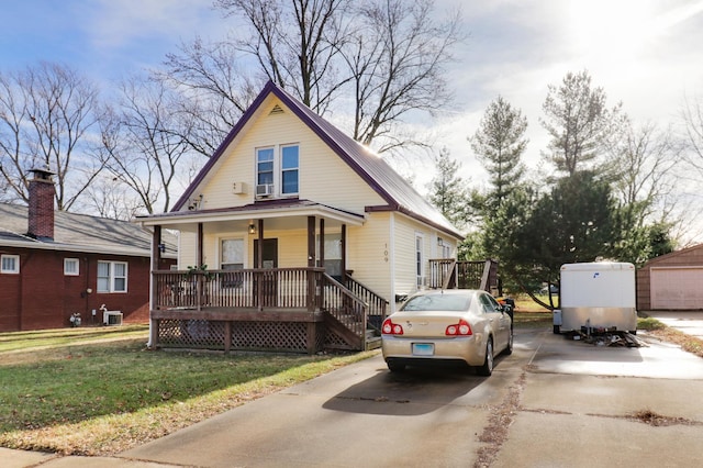 view of front facade with central air condition unit, an outbuilding, covered porch, and a front yard