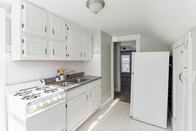 kitchen with white appliances, backsplash, lofted ceiling, white cabinets, and sink