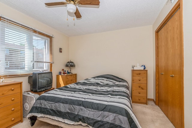 carpeted bedroom with ceiling fan, a textured ceiling, and a closet