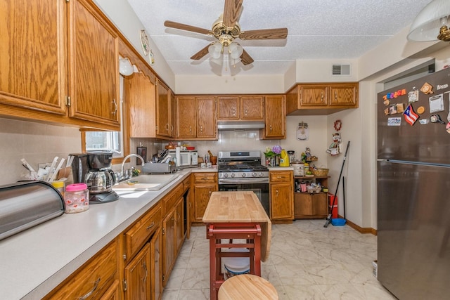 kitchen with a textured ceiling, ceiling fan, sink, and appliances with stainless steel finishes