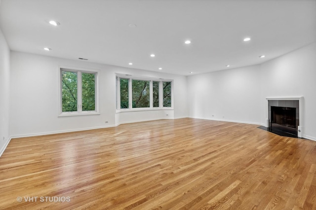 unfurnished living room featuring a tile fireplace and light wood-type flooring