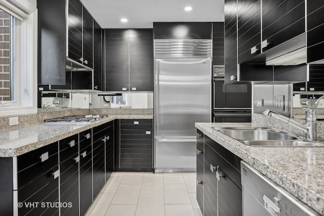 kitchen featuring light stone counters, sink, stainless steel appliances, and light tile patterned flooring