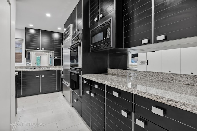 kitchen featuring appliances with stainless steel finishes, light tile patterned floors, and light stone counters