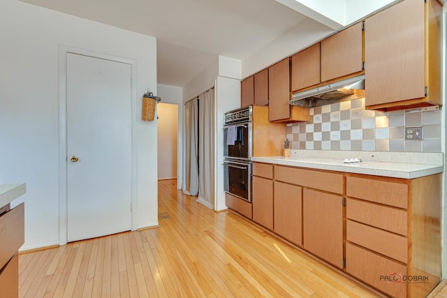 kitchen featuring double wall oven, light hardwood / wood-style flooring, and backsplash