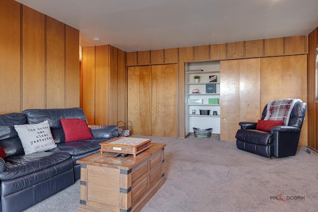 living room featuring built in features, light colored carpet, and wood walls