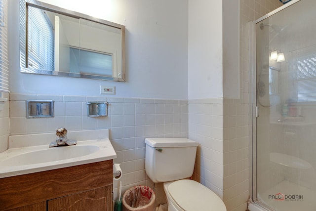 bathroom with vanity, a shower with shower door, tile walls, and toilet