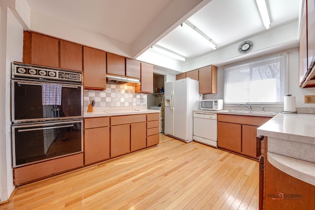 kitchen featuring sink, white appliances, decorative backsplash, and light wood-type flooring