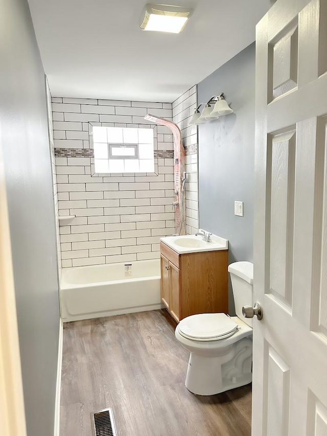 full bathroom featuring hardwood / wood-style flooring, vanity, toilet, and tiled shower / bath