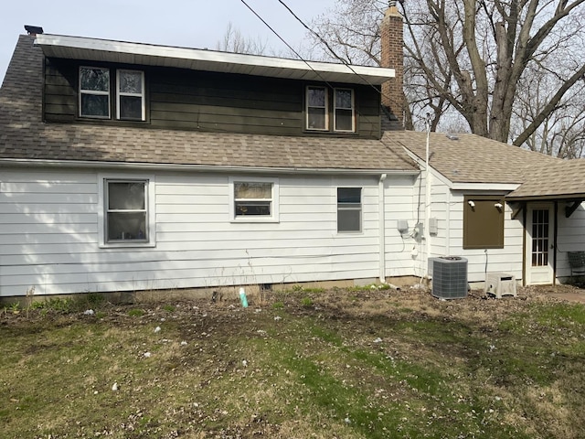 back of house with central air condition unit and a yard