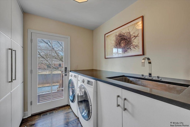 laundry area featuring independent washer and dryer, cabinets, dark hardwood / wood-style floors, and sink