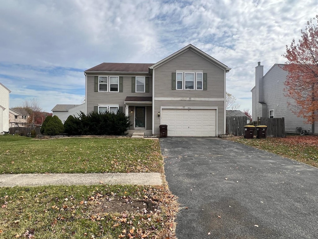 view of property featuring a garage and a front lawn