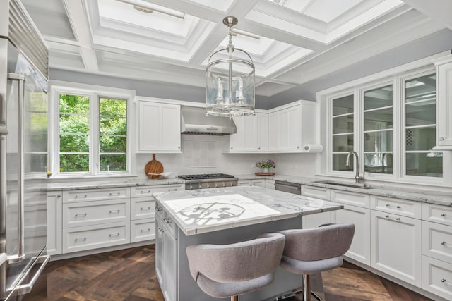 kitchen featuring light stone countertops, sink, decorative light fixtures, a kitchen island, and exhaust hood