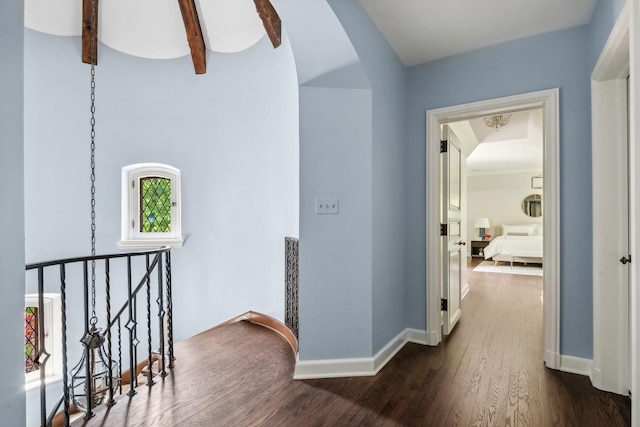 corridor featuring a wealth of natural light, dark hardwood / wood-style flooring, and beamed ceiling