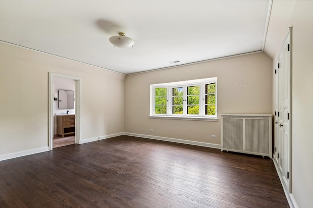 spare room featuring crown molding, radiator heating unit, and dark hardwood / wood-style floors