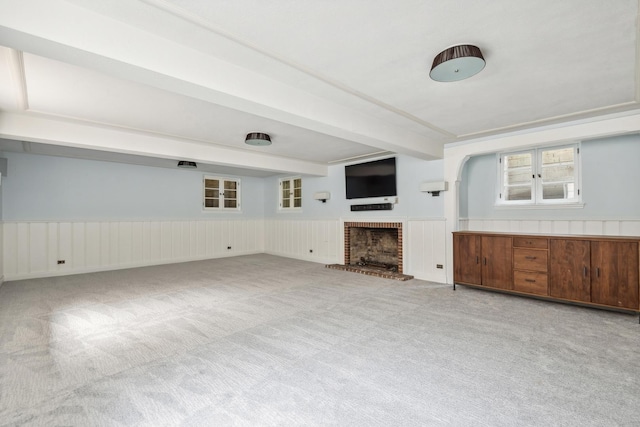 unfurnished living room with beamed ceiling, a fireplace, and light carpet