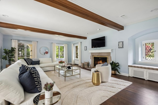 living room with beam ceiling, radiator, a high end fireplace, crown molding, and hardwood / wood-style floors