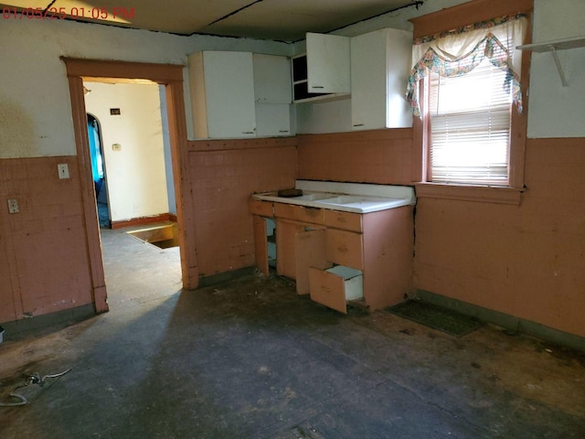 kitchen featuring concrete floors and white cabinetry