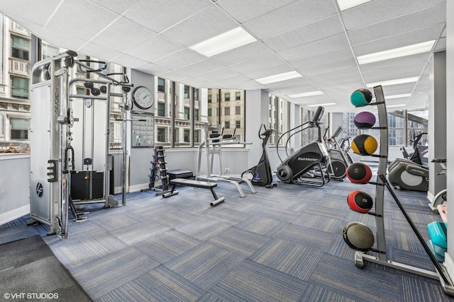 workout area with carpet floors, baseboards, and a paneled ceiling