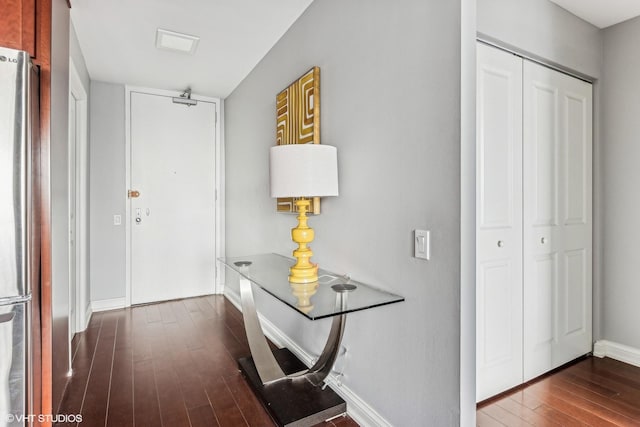 corridor featuring dark wood-type flooring and baseboards