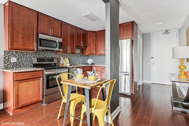 kitchen with stainless steel appliances, visible vents, baseboards, backsplash, and dark wood finished floors