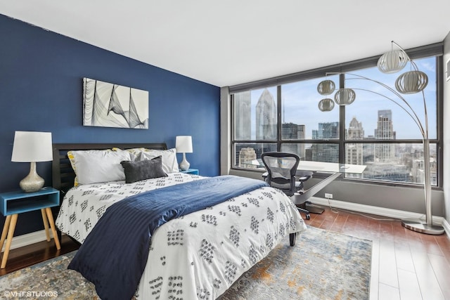 bedroom featuring a view of city, baseboards, and wood finished floors