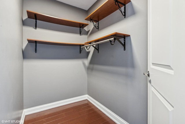 walk in closet with dark wood-type flooring