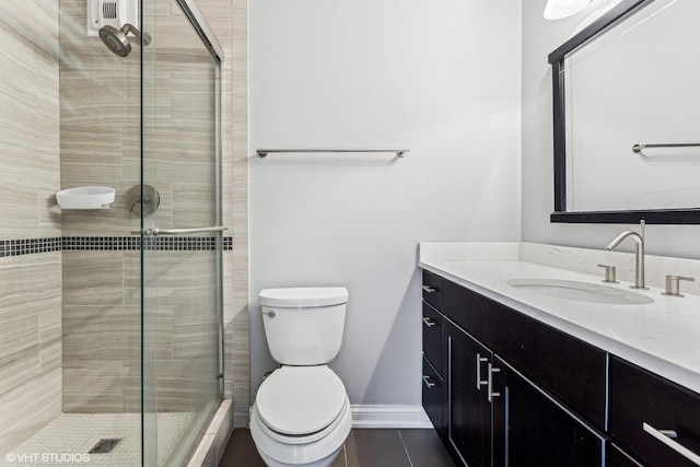 bathroom with toilet, vanity, baseboards, tile patterned floors, and a stall shower