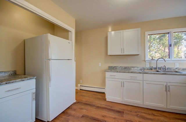 kitchen with a baseboard heating unit, white refrigerator, sink, light hardwood / wood-style flooring, and white cabinetry