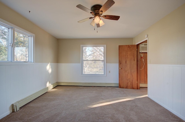 empty room with a wall mounted AC, light carpet, ceiling fan, and a baseboard radiator