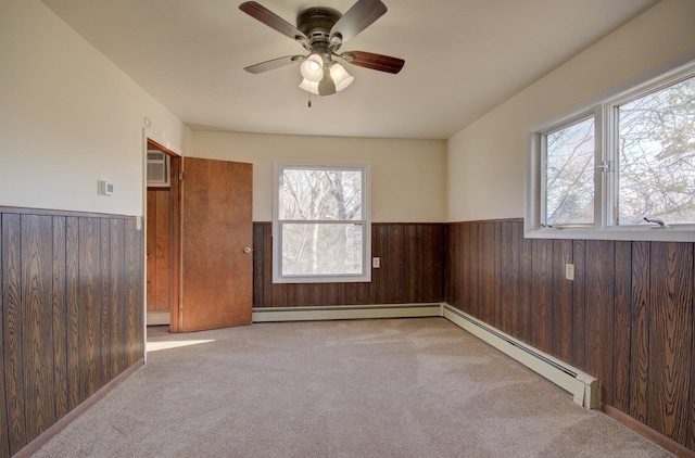 spare room with light carpet, a wealth of natural light, and wood walls