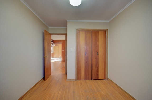 unfurnished bedroom featuring light wood-type flooring, ornamental molding, and a closet