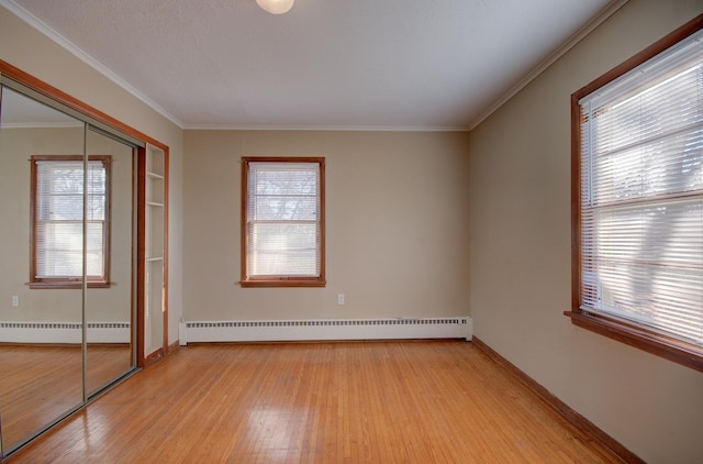 unfurnished bedroom featuring multiple windows, a closet, a baseboard radiator, and light hardwood / wood-style floors